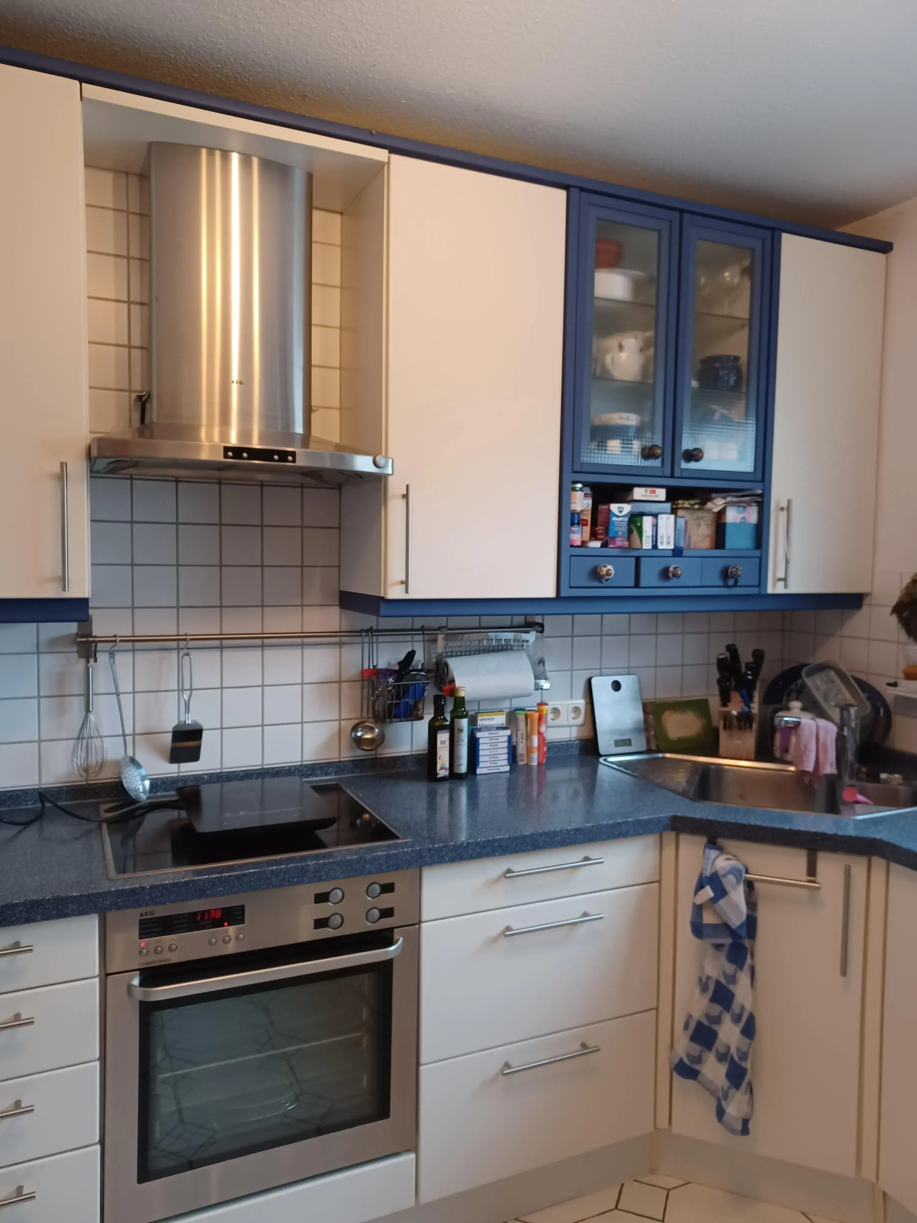 Moderne Küche mit blauen und weißen Schränken, Elektroherd und Spülbecken.