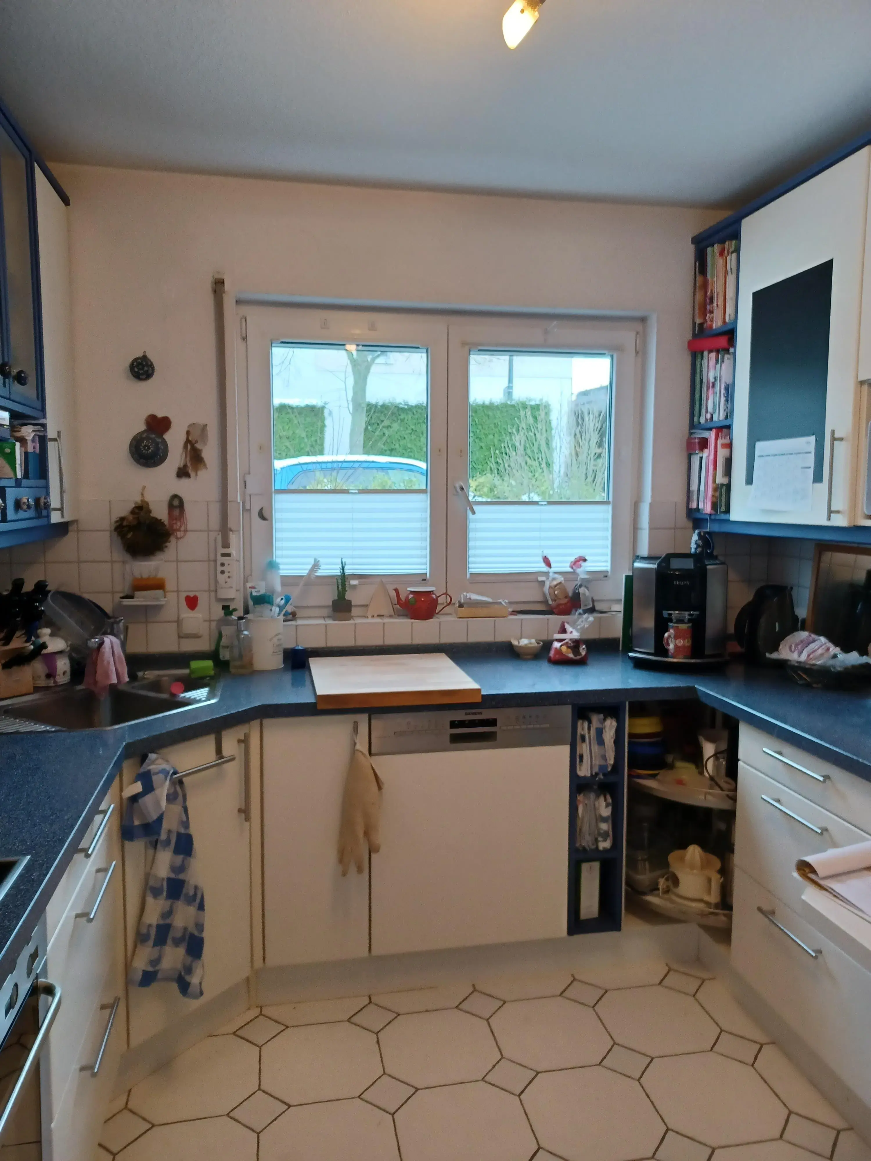 Helle Küche mit blauer Arbeitsfläche, Spülbecken und großem Fenster.
